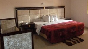 Un dormitorio con cama, mesitas de noche, un espejo y una manta roja.