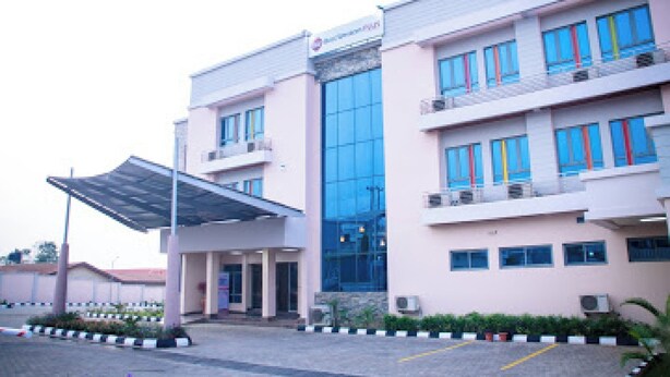 A modern building with a covered entrance, large windows, and a sign indicating a medical facility. - Room-best Western Plus-guest Room (Ibadan)