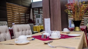 A dining table set with white tableware, a vase with flowers, and a menu stand. - Room-best Western Plus-guest Room (Ibadan)
