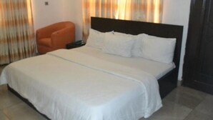 A hotel room with a bed, a chair, and curtains. - Room-blueseasons Hotel & Suites- Guest R (Lagos)