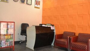 A reception area with a desk, two chairs, a magazine rack, and a wall with a textured pattern. - Room-blueseasons Hotel & Suites- Guest R (Lagos)