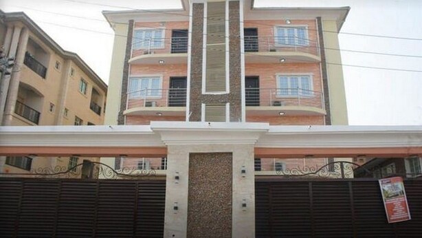 A multi-story residential building with a central vertical feature, balconies, and a gated entrance. - Room-blueseasons Hotel & Suites- Guest R (Lagos)