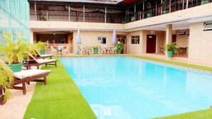 An indoor swimming pool with lounge chairs and potted plants. - Room-chelsea Hotel - Guest Room (Abuja)