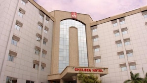 A multi-story building with a prominent arched entrance and a sign reading 'CHELSEA HOTEL.' - Room-chelsea Hotel - Guest Room (Abuja)
