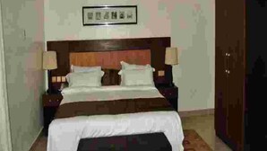 A hotel room with a bed, nightstands, a framed picture on the wall, and a wardrobe.