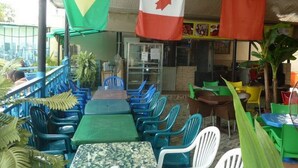 A restaurant with outdoor seating, tables, chairs, and flags of Brazil, Canada, and China. - Room-definite Destiny Hotel - Guest Roo (Asaba)