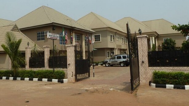 A gated residential area with multiple houses, a sign indicating a school, and a parked car. - Room-definite Destiny Hotel - Guest Roo (Asaba)