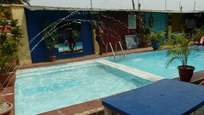 A swimming pool with a blue edge, surrounded by potted plants, and a blue bench. - Room-definite Destiny Hotel - Guest Roo (Asaba)