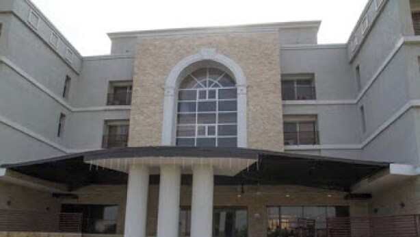 A multi-story building with a central arched window, columns, and a covered entrance area. - Full Moon Hotel - Premiere (Owerri)