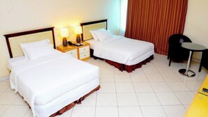 Ein Hotelzimmer mit zwei Betten, einem Nachttisch mit Lampen, einem kleinen Tisch und einem Stuhl.