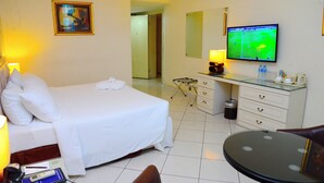 Ein Hotelzimmer mit Bett, Nachttisch, Lampe, Fernseher und einem kleinen runden Tisch.