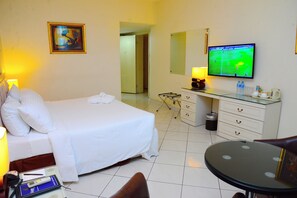A hotel room with a bed, bedside table, lamp, TV, and a small round table.