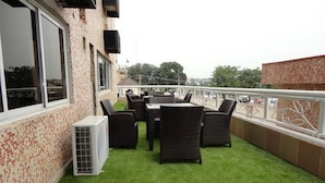 An outdoor patio with a table and chairs, a small air conditioning unit, and a view of the surrounding area. - Room-grand Ibro Hotel - Guest Room (Abuja)