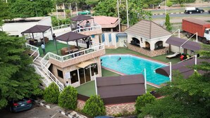 A pool area with a swimming pool, lounge chairs, and a covered seating area. - Room-grand Ibro Hotel - Guest Room (Abuja)