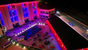 An aerial view of a hotel with a swimming pool, outdoor seating, and a street in the background. - Room-hampton Towers & Spa - Guest Room (Asaba)