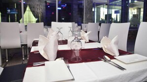 A dining table set with white napkins, silverware, and a clear glass. - Room-hampton Towers & Spa - Guest Room (Asaba)