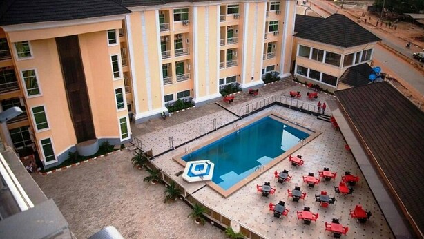 A multi-story hotel with a swimming pool, outdoor seating, and a view of the surrounding area. - Room-hampton Towers & Spa - Guest Room (Asaba)
