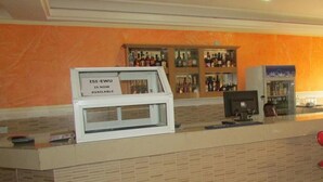 Zona de recepción de hotel con mostrador, un cartel que indica disponibilidad y un bar con diversas botellas.