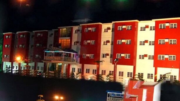A multi-story hotel with balconies, a swimming pool, and a well-lit facade. - Room-hotel De Bently - Guest Room (Abuja)
