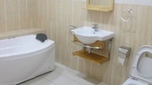A bathroom with a bathtub, a sink, and a toilet. - Room-joy House Hotel - Guest Room (Abuja)