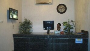 A reception desk with a computer monitor, a clock, and a sign indicating a hotel. - Room-joy House Hotel - Guest Room (Abuja)