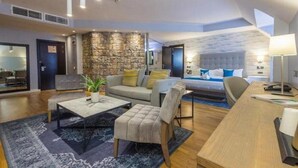 A modern living room with a stone accent wall, a sofa, a coffee table, and a dining area. - Room-leola Hotel, Lagos-guest Room (Lagos)