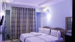 Een slaapkamer met een tweepersoonsbed, een nachtkastje, een spiegel en een airconditioning.