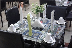 Una mesa de comedor dispuesta con servilletas blancas, un florero con flores blancas y un menú.