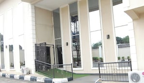 Un edificio con una entrada amplia y abierta, una escalera que sube y un portón metálico.