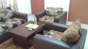 Uma sala de estar com sofá, mesa de centro e uma porta ao fundo.