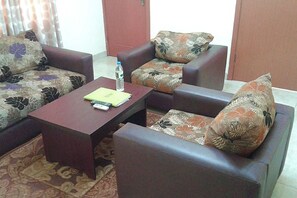 Una sala de estar con un sofá, una mesa de centro y una puerta al fondo.