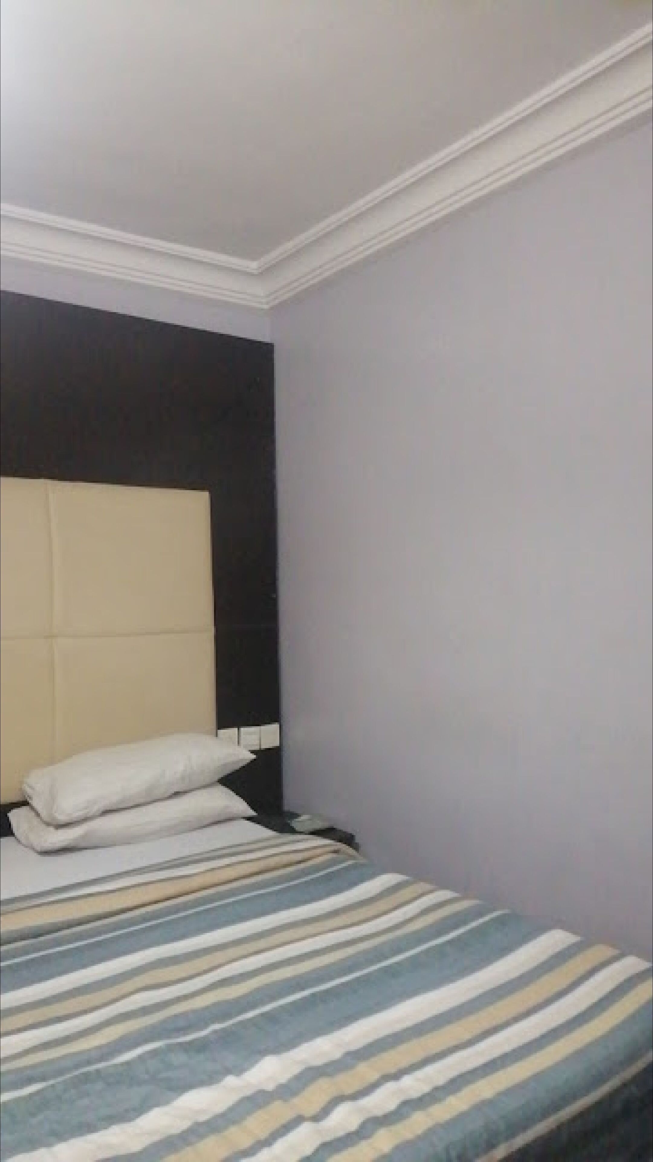 A room with a bed, a headboard, and a striped blanket.