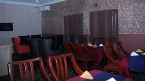 A conference room with wooden chairs, tables with blue tablecloths, and a patterned wall. - Room-royal Park Hotel & Suite - Guest Ro (Asaba)