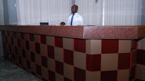 A reception desk with a checkered pattern and a person standing behind it. - Room-royal Park Hotel & Suite - Guest Ro (Asaba)