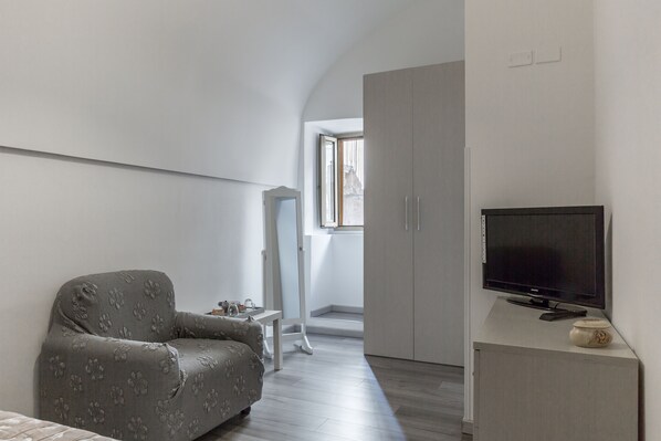 Une chambre à coucher avec un lit, une télévision, une armoire et une fenêtre.