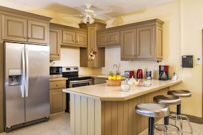 A kitchen with a refrigerator, stove, microwave, and a coffee maker. - Golden View #115 - by Zenbreak (Holetown)
