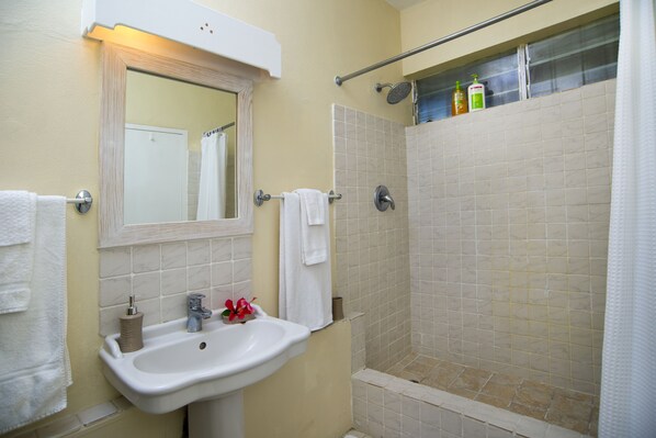Un baño con lavamanos, espejo y ducha.