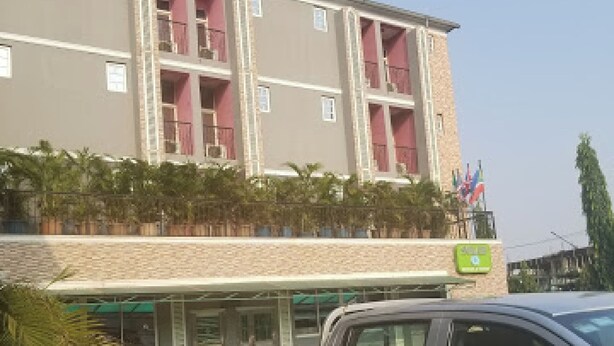 A multi-story building with a flat roof, a parking area, and a vehicle parked in front. - Room-aotel Hotel - Guest Room (Lagos)