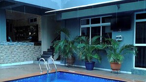 An indoor swimming pool with a ladder, potted plants, and a modern building facade. - Room-aotel Hotel - Guest Room (Lagos)