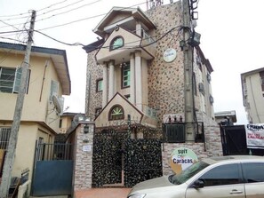 Um edifício com fachada de pedra, entrada com portão e uma placa indicando 'SUIT LAS CARACAS'.