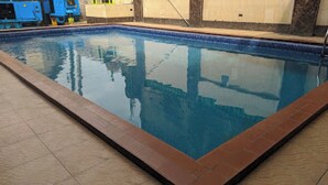 Ein Schwimmbecken mit einem gefliesten und einem umlaufenden Holzdeck.