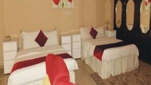 Habitación de hotel con dos camas, una mesita de noche, una lámpara y un espejo.