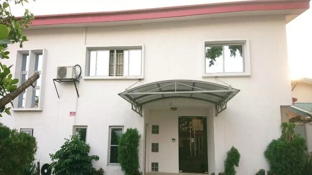 Un edificio blanco con techo plano, entrada cubierta y varias ventanas.