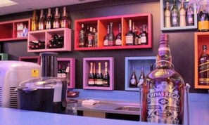 A bar area with shelves of liquor bottles, a Chivas Regal bottle prominently displayed, and a coffee machine.