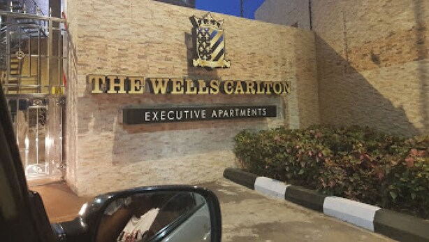 A building with a sign reading 'THE WELLS CARLTON EXECUTIVE APARTMENTS'. - Room-the Wells Carlton - Guest Suite (Abuja)