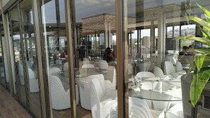 A modern interior with glass walls, white furniture, and a view of the city. - Room-the Wells Carlton - Guest Suite (Abuja)