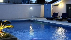 A swimming pool with lounge chairs and a small plant. - Room-waxride Residence - Guest Room (Abuja)