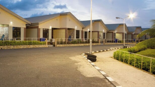 A hotel with multiple buildings, a paved parking area, and street lamps. - Room-whispering Palms Resort-guest Room (Lagos)