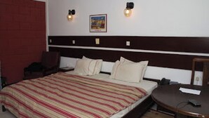 A hotel room with a bed, a desk, and a chair. - Room-whispering Palms Resort-guest Room (Lagos)