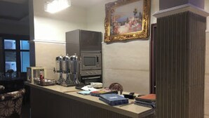 A kitchen with a microwave, oven, and cabinets, a framed painting on the wall, and a counter with various items. - Room-world Lilies Hotel-guest Room (Ibadan)